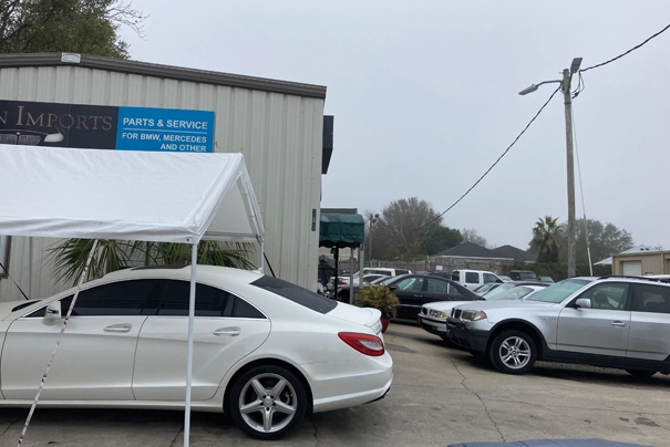 A white car parked beside Destine import auto repair shop