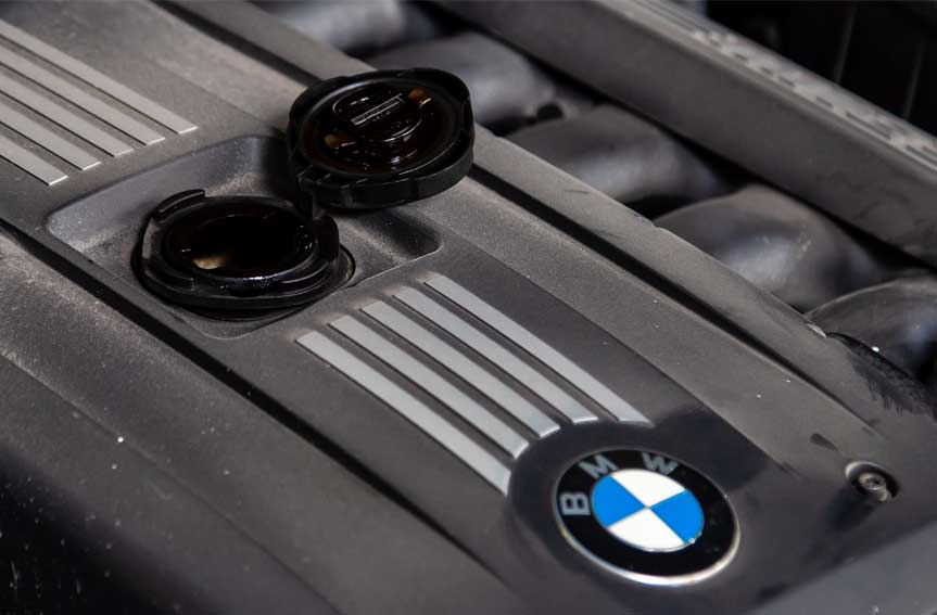 Di - BMW car engine with emblem and open engine filler neck for topping up oil due to malfunction and high consumption and combustion